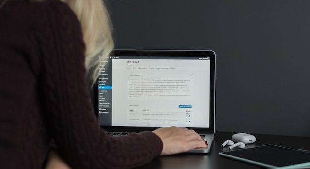 Une femme blonde assise à un bureau et travaillant sur un ordinateur portable