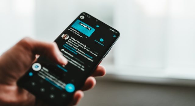 Personne tenant un téléphone avec un flux Twitter ouvert dessus