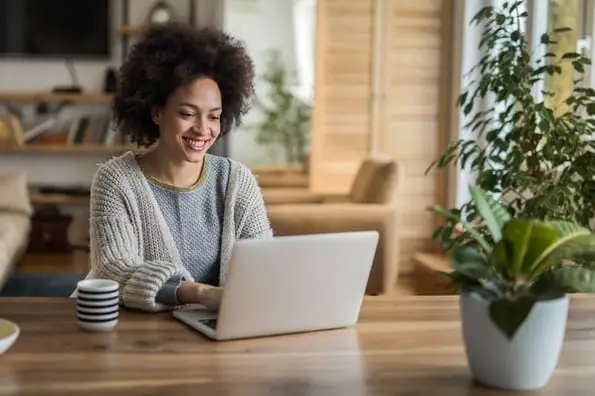 Seorang wanita duduk di mejanya dan menulis posting blog dari laptopnya