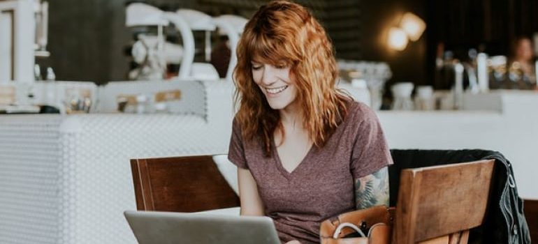 Una donna seduta a una scrivania, guardando il suo laptop e sorridente