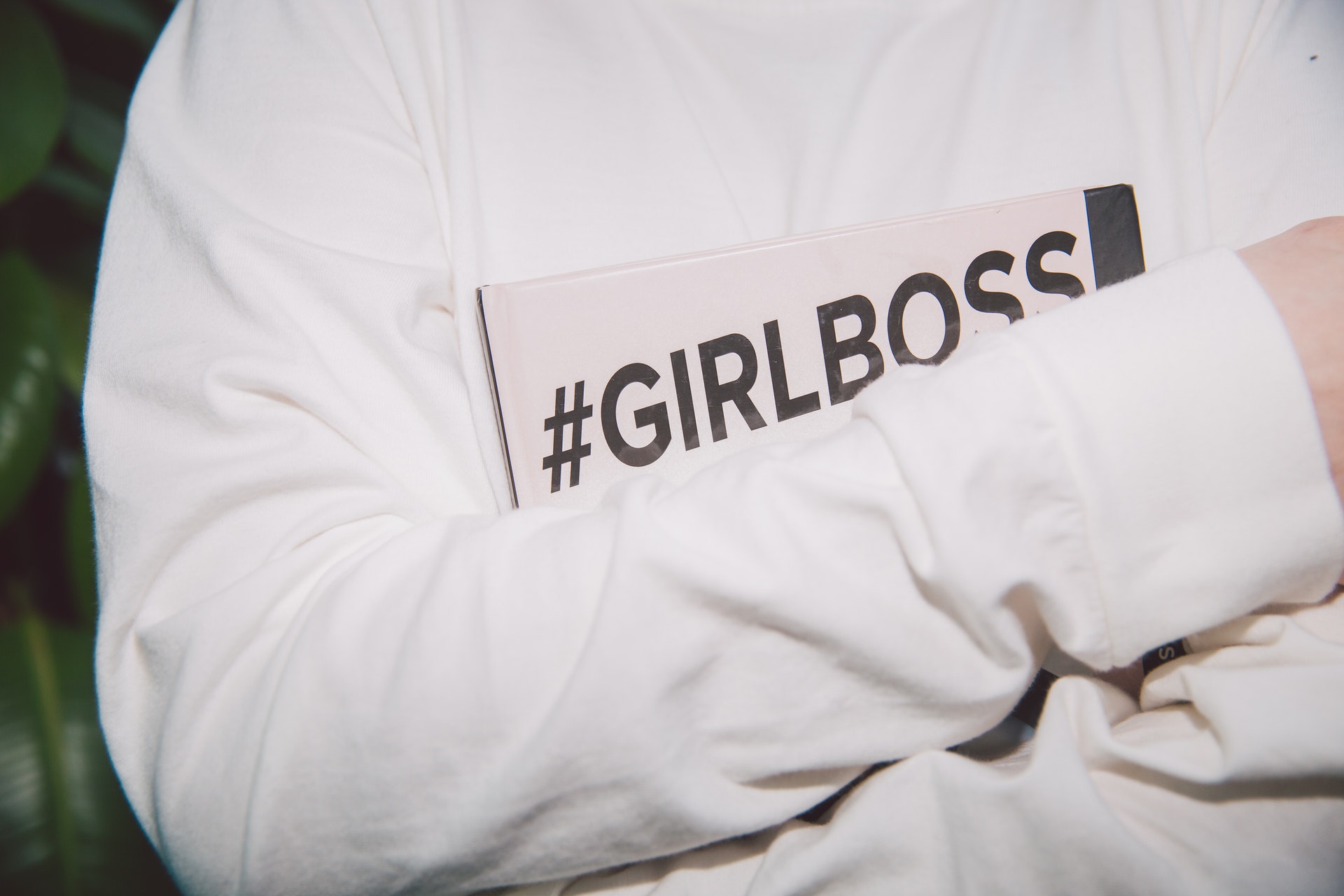 拿著帶有girlboss標籤的筆記本的人