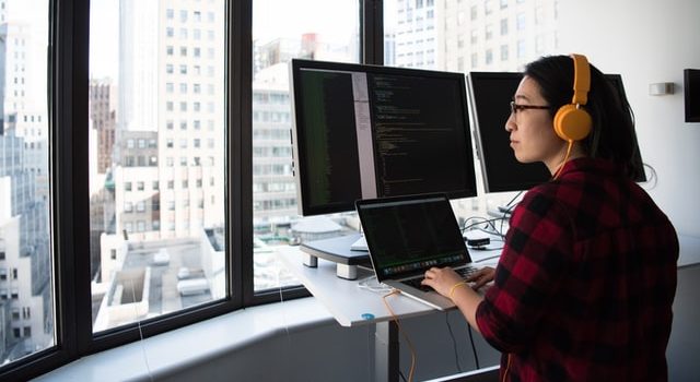 Personne avec un casque jaune programmant devant une grande fenêtre