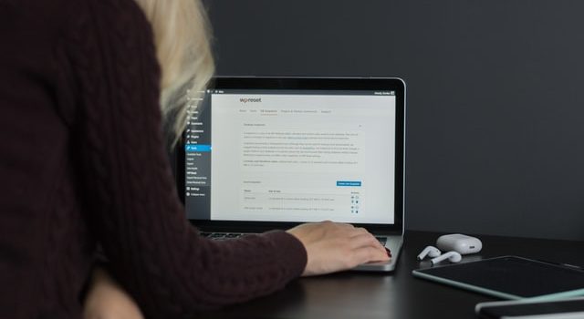 Femeie blondă care scrie un blog în WordPress pe laptopul ei